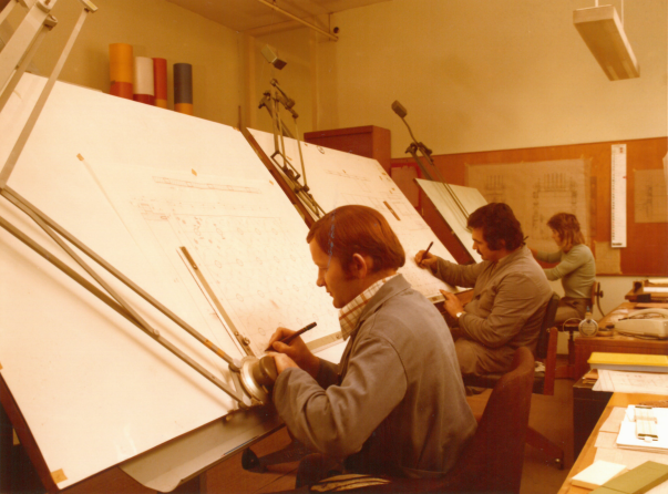 Retro photo of a design office in which three men are working at large drawing tables.